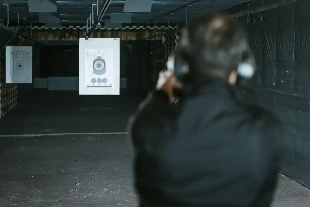 Student in ear protection aiming at a paper target during live-fire training