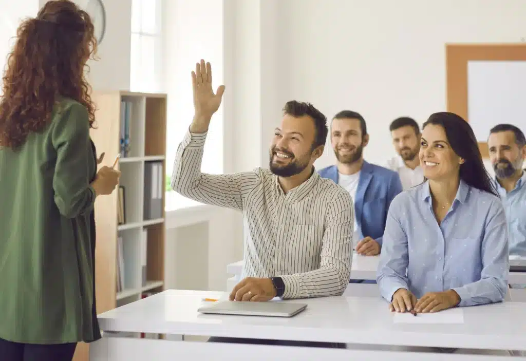 Adult student raising his hand to ask a question during a security guard training class