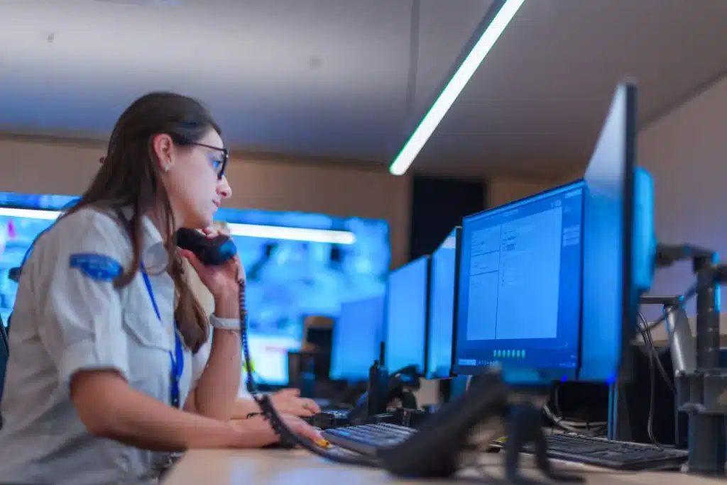 Uniformed security officer taking a call at a monitoring desk