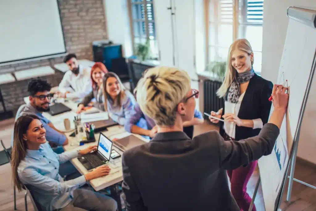 Trainer presenting at a whiteboard to staff around a conference table