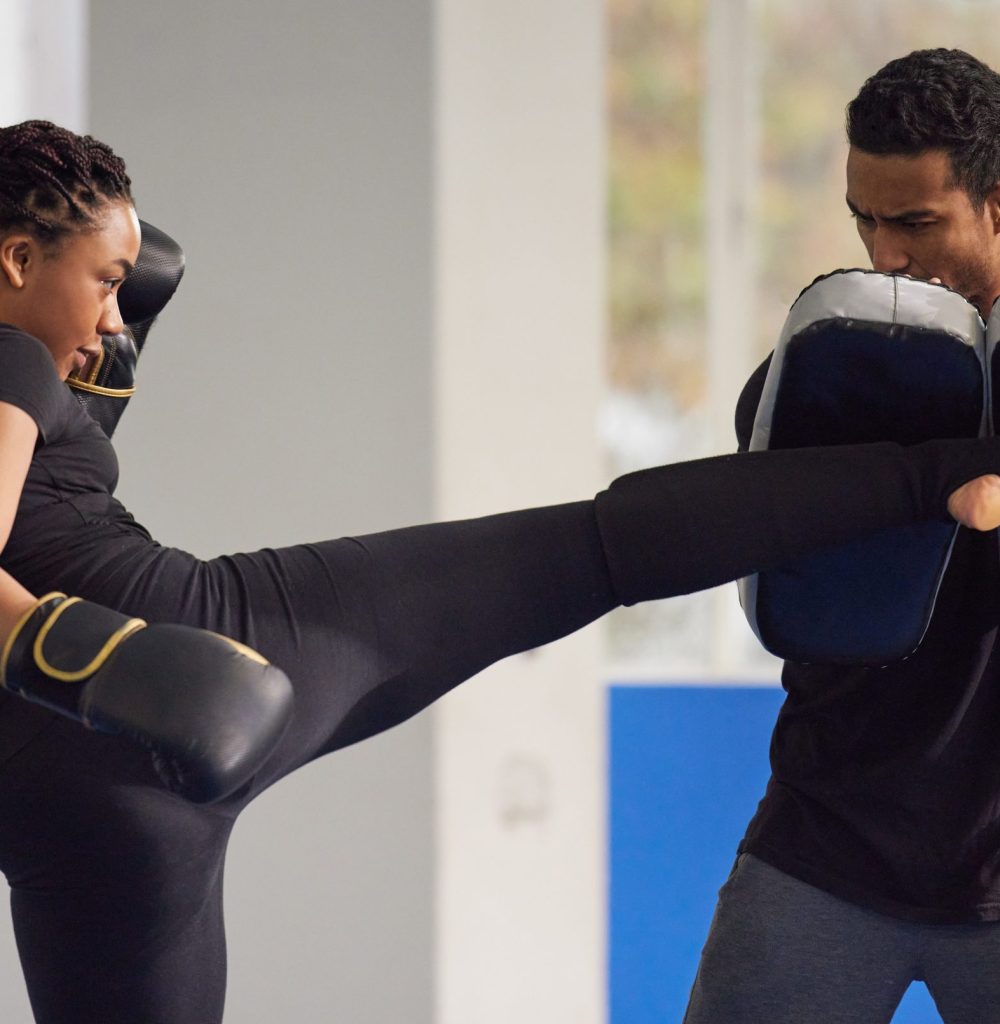 Shot of a young woman practicing kickboxing with her trainer in a gym. About WSC Defense